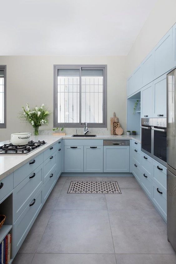 a pastel blue kitchen with shaker cabients, white granite countertops and black fixtures and handles is amazing