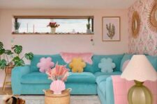 a pastel living room with blush walls, an accent wall, a turquoise sofa with pastel pillows, a side table and a potted plant