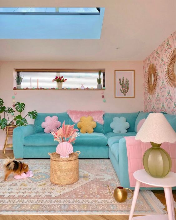 a pastel living room with blush walls, an accent wall, a turquoise sofa with pastel pillows, a side table and a potted plant
