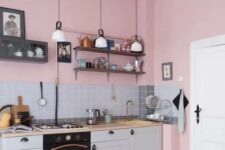 a pink kitchen with grey lower cabinets, butcherblock countertops, a grey tile backsplash, pendant lamps and a printed tile floor
