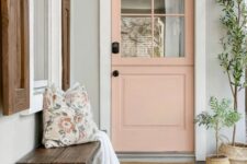 a pretty front porch with a printed tile floor, a stained bench with pillows, a salmon pink Dutch door, potted plants and a rug