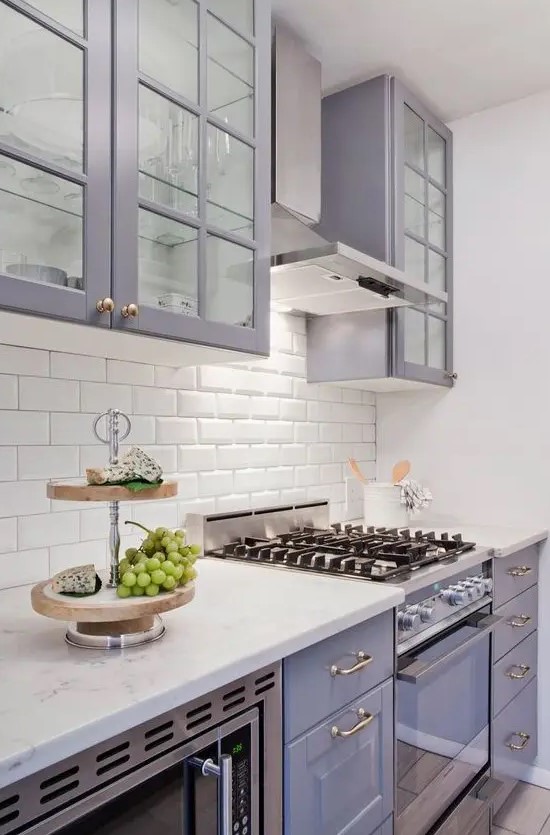 a pretty lilac kitchen with a white subway tile backsplash and white countertops plus brass and gold touches