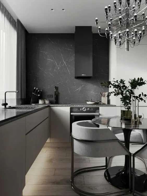 a refined contemporary kitchen with sleek neutral cabinets, black countertops and a black marble backsplash and an eating zone