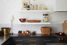 a refined vintage kitchen wiht navy flat panel cabinets, black granite countertops, open shelving and brass and gold touches