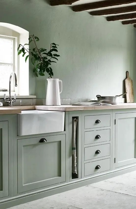 a sage green kitchen with a white ceiling and appliances plus black handles looks ethereal and very natural