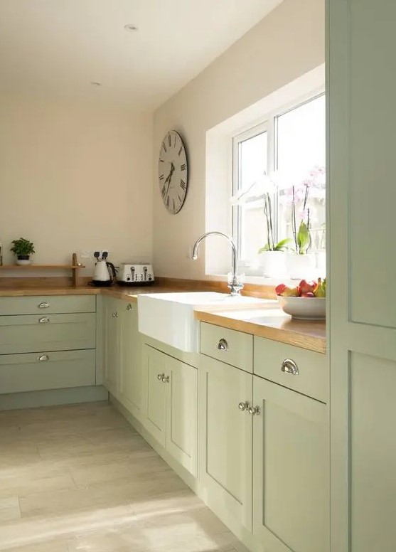 a sage green kitchen with shaker cabinets, butcherblock countertops, no upper cabinets for an airy feeling in the space