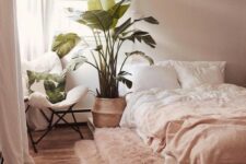 a simple boho bedroom with light pink walls, light pink bedding and a rug, a pallet bed and a comfy chair