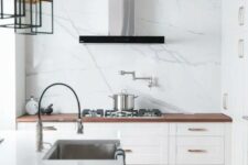 a small and cool white kitchen with shaker cabinets and a white quartz backsplash, butcherblock and quartz countertops