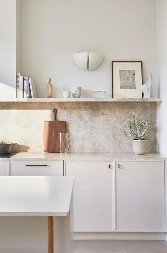 a small and elegant creamy kitchen with a grey quartz backsplash and countertops plus an open shelf is amazing