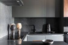 a small minimalist kitchen with grey tiles, sleek grey cabinets, black granite countertops and black fixtures