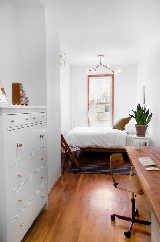 a small neutral bedroom with a bed and nightstands by the window, a dresser and a long desk plus a chair is cool