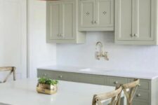 a small sage green kitchen with shaker and flat panel cabinets, a white subway tile backsplash and white countertops plus a catchy brushed lamp