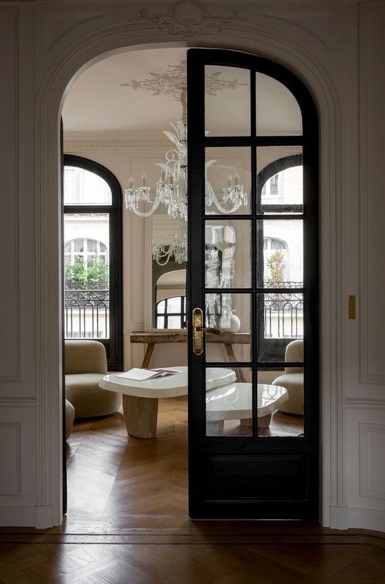 a sophisticated French chic space with black frame French arched doors leading to it, these doors highlight the sophistication of the style
