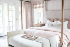 a sophisticated bedroom with an accent wall, a frame bed with dusty pink and white bedding, an upholstered bench and a cool chandelier