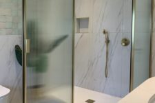 a sophisticated neutral bathroom with a shower with fluted glass and gold framing, white marble and mother of pearl tiles