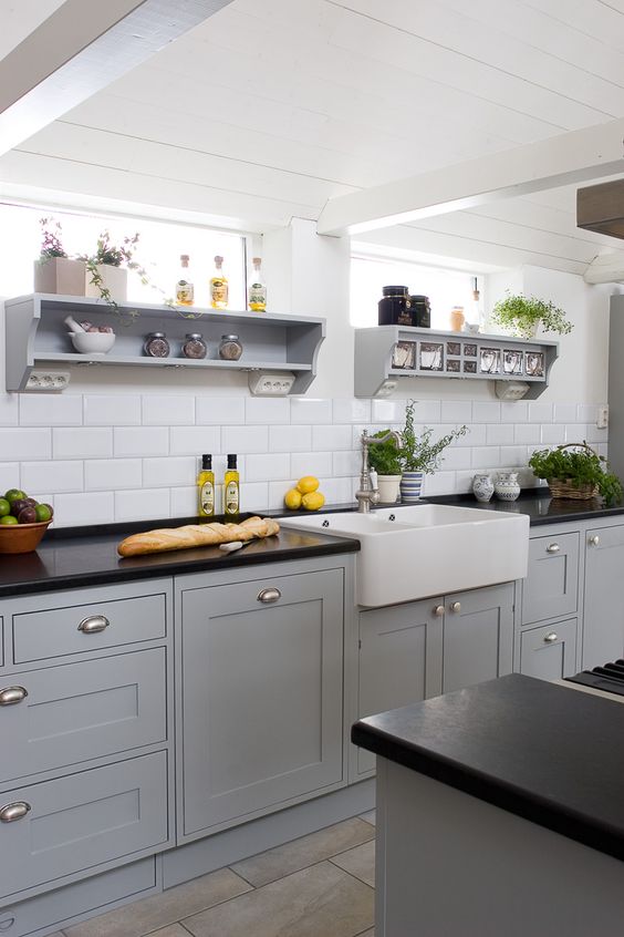 a stylish grey kitchen with shaker cabinets, black granite countertops, open shelves and potted herbs is all cool