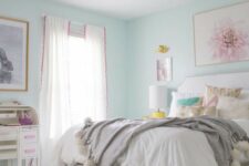 a teen girl bedroom with mint blue walls, a white bed and poufs, neutral bedding, some artworks and gold touches