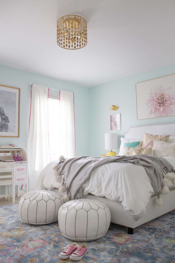 a teen girl bedroom with mint blue walls, a white bed and poufs, neutral bedding, some artworks and gold touches