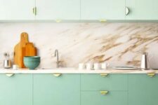 a two-tone kitchen with mint green and brighter green cabinets, a marble backsplash and countertops, gold pulls is amazing