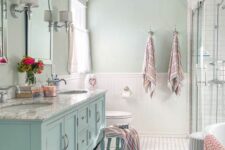 a vintage-inspired pastel green bathroom with an aqua vanity and light green walls, a shower and a vintage chandelier
