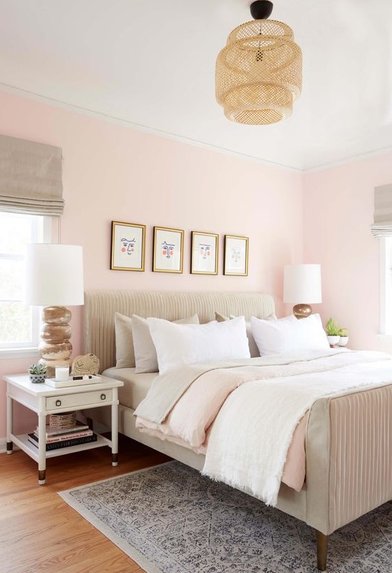 a welcoming eclectic bedroom with light pink walls, neutral textiles and upholstery, a woven lamp and white nightstands