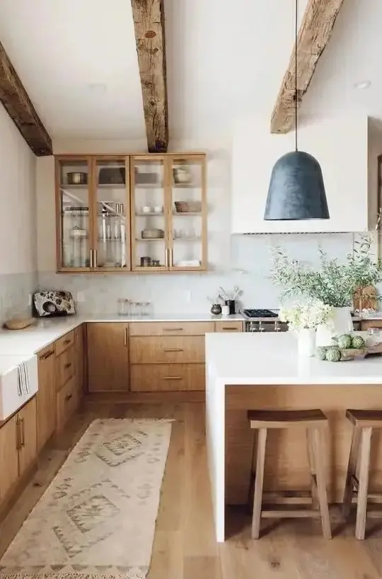 a welcoming modern farmhouse kitchen with light-stained cabinets, wooden beams and stools that warm up the space