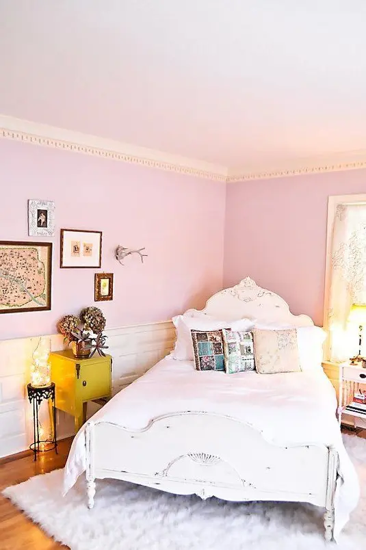 a whimsy bedroom with light pink walls, a gallery wall, a shabby chic bed and printed pillows plus lights