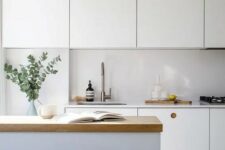 a white Scandinavian kitchen with a sleek white backsplash, a kitchen island with a butcherblock countertop