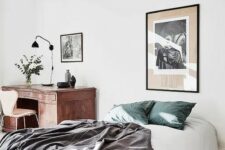 an airy and light bedroom with a bed and a vintage wooden desk in the corner, some artwork to make it more beautiful and stylish