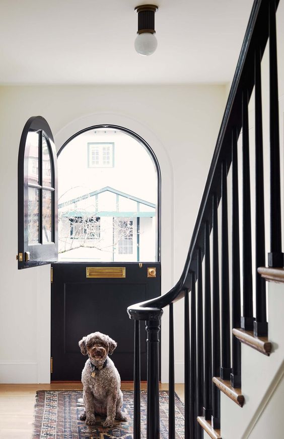 an arched Dutch door in black, with brass fixtures, accents the entryway and makes a statement outside, too