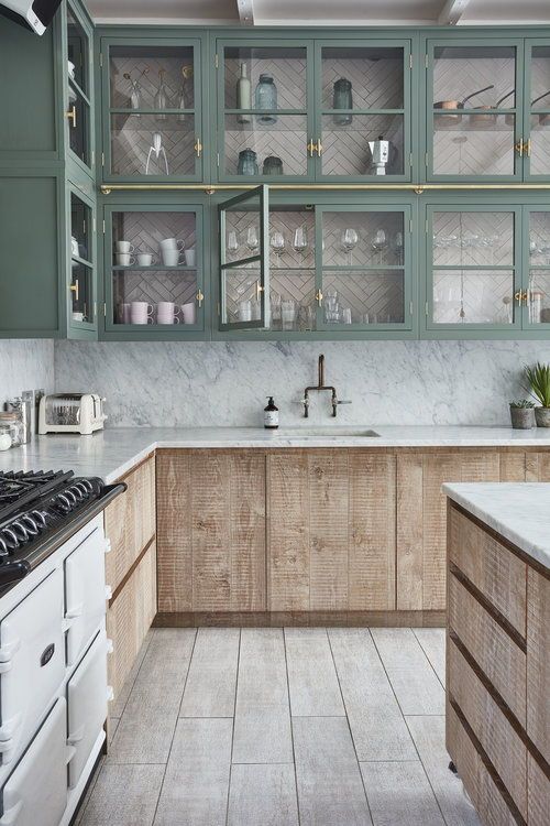 an eye-catchy kitchen with textural wood and green glass front cabinets, white stone countertops and a backsplash