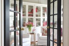 black French doors with gold knobs accent the space and contrast a neutral space with their bold color