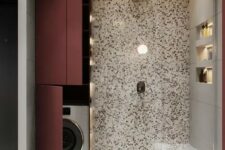 03 a bright bathroom done with terrazzo with a washing machine hidden by the shower space and behind burgundy doors