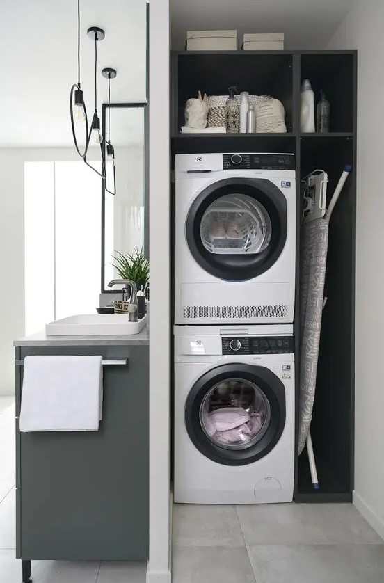 a compact concealed laundry area combining washing machine, dryer and ironing table in a single unit in a bathroom