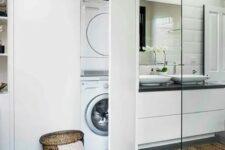07 a modern bathroom clad with grey and white tiles, a white vanity with sinks, a large storage unit with a washing machine hidden