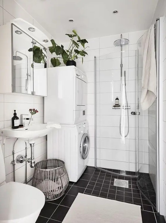 a black and white Scandinavian bathroom with white and black tiles, a shower in the corner, a washing machine and a dryer and a sink