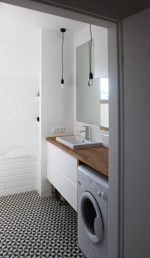 a contemporary black and white bathroom with a printed tile floor, white subway tiles, a floating vanity, a washing machine and pendant bulbs