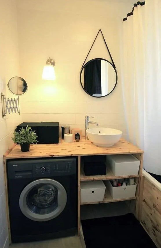 a small black and white bathroom with a black washing machine built in the vanity, a small mirror and a shower space