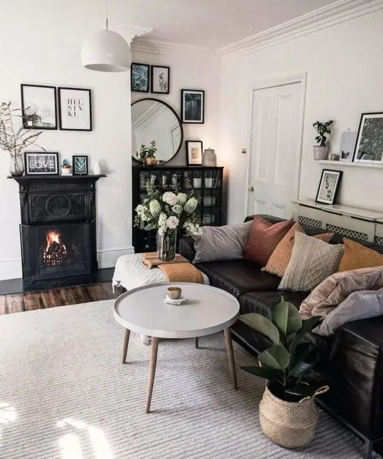 a Scandi living room with a black fireplace, a black sofa, a couple of coffee tables, a black credenza and potted plants