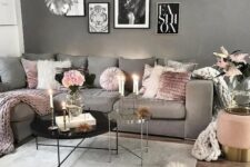 a Scandi living room with a grey wall and a grey sofa, pink pillows and blankets, catchy scallop pendant lamps