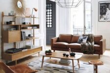 a Scandi meets modern living room with a tan leather sofa, light-stained furniture and a leather Eames rocker, a printed rug and a pendant lamp