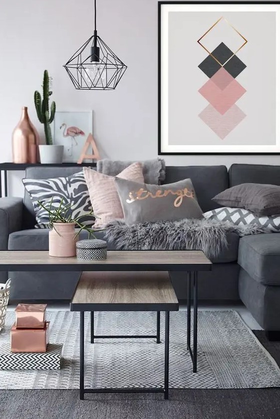 a Scandinavian living room with a graphite grey sectional, grey and pink pillows, two coffee tables, copper and pink touches