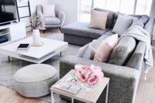 a Scandinavian living room with a grey sectional, a TV and a TV unit, a tiered coffee table, pink pillows and blooms