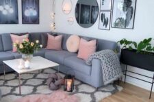 a Scandinavian living room with a grey sectional, a coffee table, a black planter on legs, a gallery wall and a printed rug
