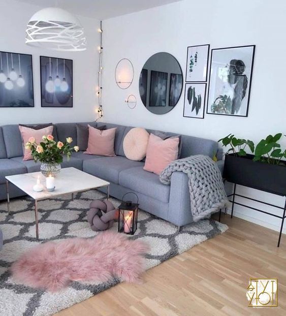 a Scandinavian living room with a grey sectional, a coffee table, a black planter on legs, a gallery wall and a printed rug