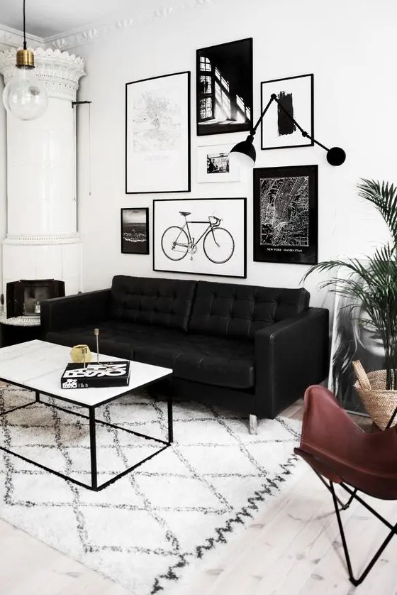 a Scandinavian living room with a white hearth, a black leather sofa, a leather butterfly chair, a coffee table and a gallery wall