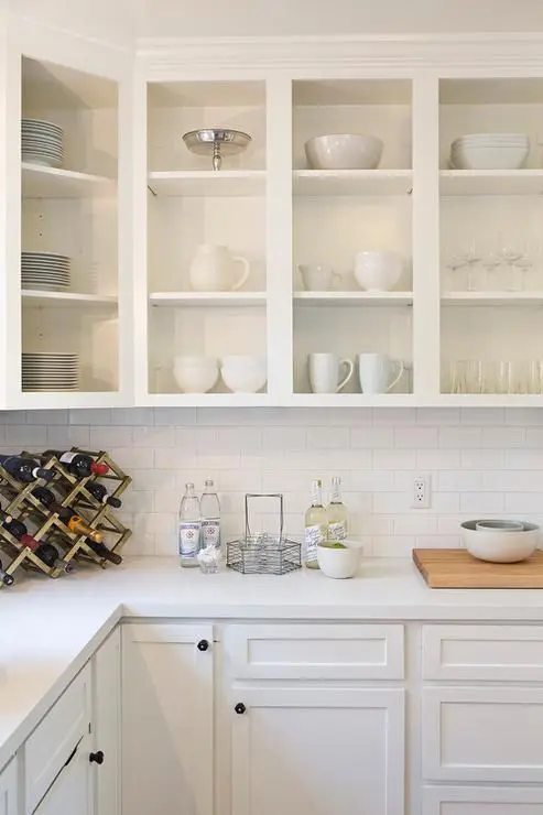 a beautiful all-white kitchen with open cabinets, shaker style ones, a white subway tile backsplash and countertops