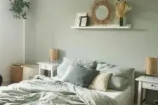 a boho sage green bedroom with white furniture, woven lamps, a ledge with a mirror, a woven pendant lamp and sage green bedding