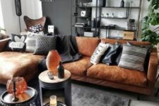 a bold living room with a black accent wlal, a tan leather sectional, black and white pillows, a rug, a storage unit and nightstands