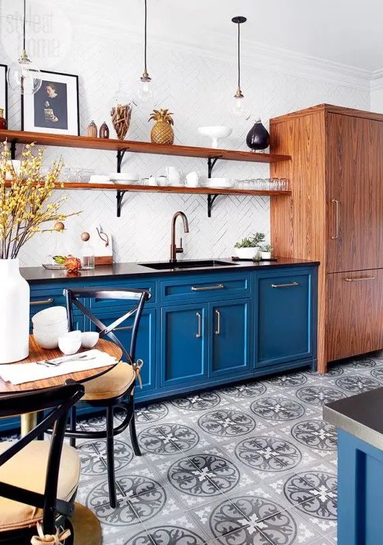 a bright blue kitchen with shaker lower cabinets, black countertops, long open shelves and a white herringbone tile backsplash is amazing
